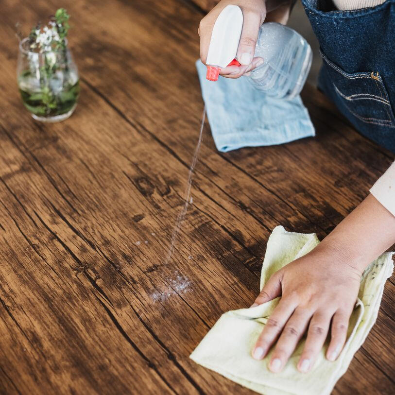 wiping a wooden table for a regular cleaning service