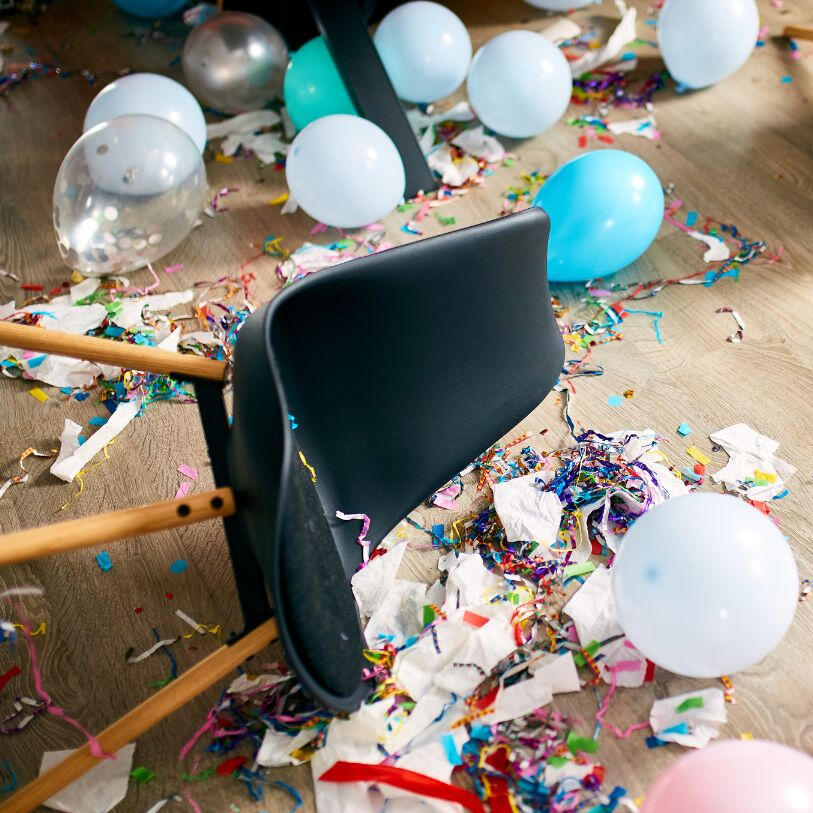 a messy room with papers, chair and balloons on the floor after a party